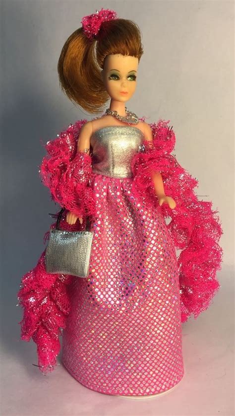 A Barbie Doll Dressed In A Pink Dress And Holding A Silver Purse With