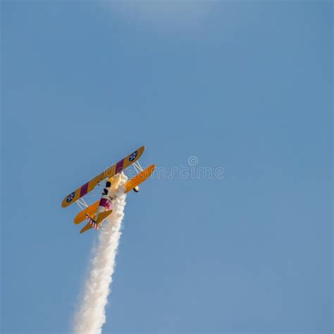 A Small Biplane Airplane Doing Acrobatic Stunts Against The Blue Sky