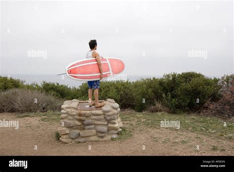 Man Holding Surfboard Looks Out Over Ocean Stock Photo Alamy