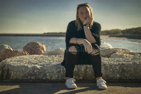 Blonde Girl Sitting On The Rocks With Cigarette In Hand Stock Image