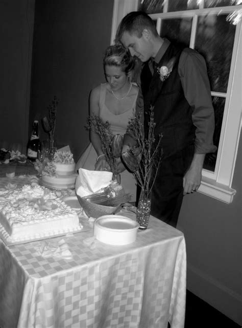 A Man And Woman Standing Next To Each Other In Front Of A Table With