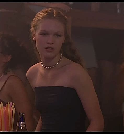 A Woman In A Strapless Dress Standing Next To Two Other Women With Pens