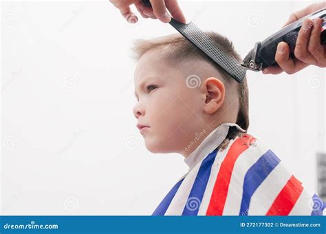 The Boy Kid Is Getting A Haircut In A Barbershop Hair Stylist Indoor