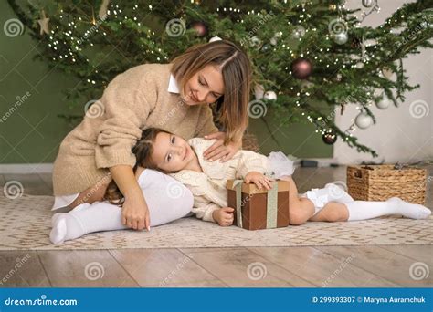 A Loving Mother Gently Strokes Her Daughter At The Christmas Tree Stock