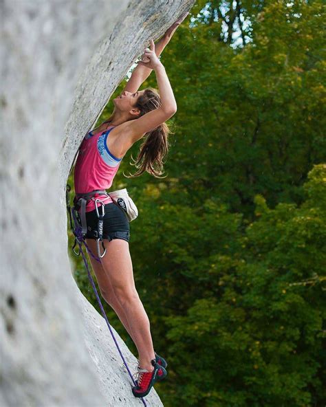 A Woman Climbing Up The Side Of A Rock