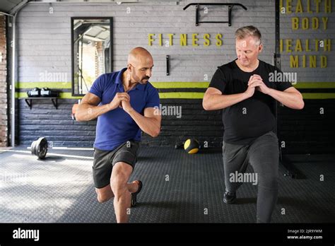 Male Personal Trainer Instructing And Assisting Mature Senior Man While