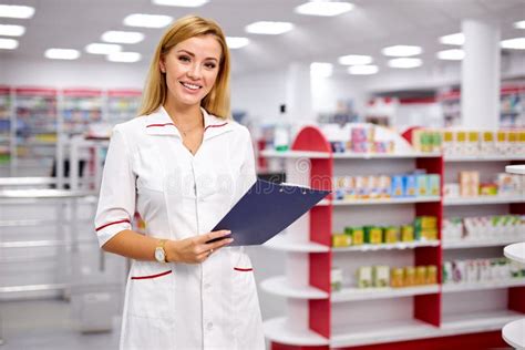 Pleasant Female Pharmacist Writing On Clipboard At Pharmacy Make Notes