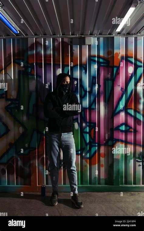 African american vandal in hoodie standing near spray paint and ...