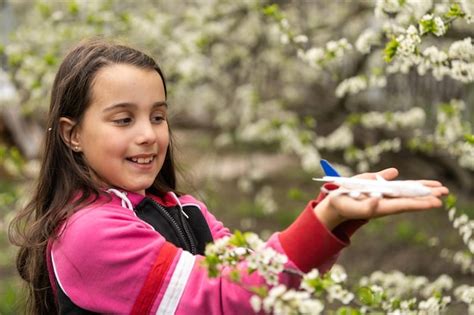 Niña con un avión de juguete en el jardín Foto Premium