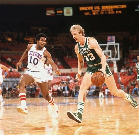 Two Men Playing Basketball On A Court With People Watching From The