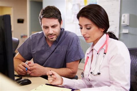 Female Doctor With Male Nurse Working At Nurses Station Royalty Free