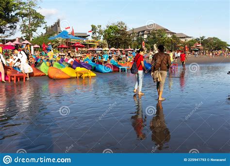 Tourists And Locals Strolling And Enjoying Sunset At Seminyak Beach In