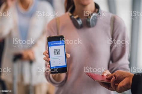 Closeup Female Traveler Showing Her Digital Boarding Pass To Ground Attendant At Checkin Counter