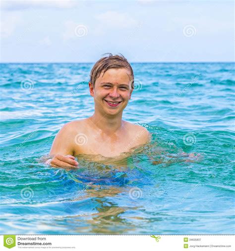 Muchacho Sonriente Que Se Coloca En El Agua Del Océano Atlántico Imagen