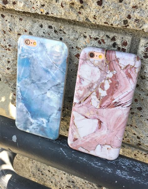 Two Marble Iphone Cases Sitting Next To Each Other On A Stone Bench In