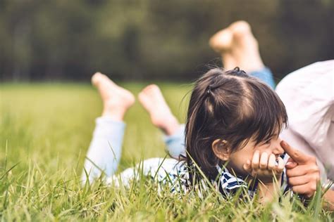 Una niña feliz y linda tendida en la hierba verde al aire libre jugando