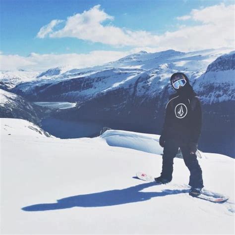 A Snowboarder Standing On Top Of A Snowy Mountain