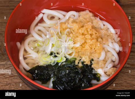 Udon in broth with Wakame seaweed, Tenkasu, spring onions, fish broth in a red bowl Stock Photo ...