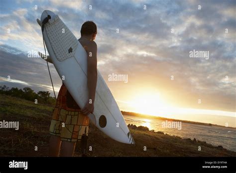 Man Holding Surfboard At Sunset Stock Photo Alamy