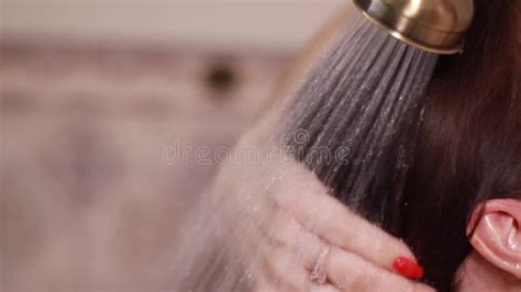 Young Brunette Woman Washing Her Long Hair Under The Shower Standing With Her Back To The Camera