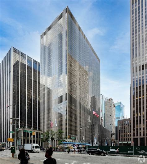 Two People Are Standing On The Sidewalk In Front Of Some Tall Buildings