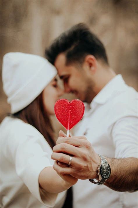 A Man And Woman Holding A Red Heart Lollipop