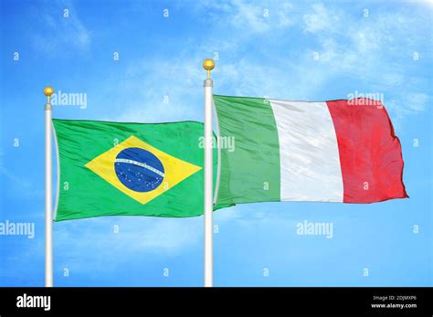 Brazil And Italy Two Flags On Flagpoles And Blue Cloudy Sky Stock Photo