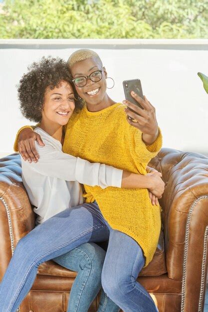 Premium Photo Smiling Diverse Lesbian Females In Love Sitting In Leather Armchair And Taking