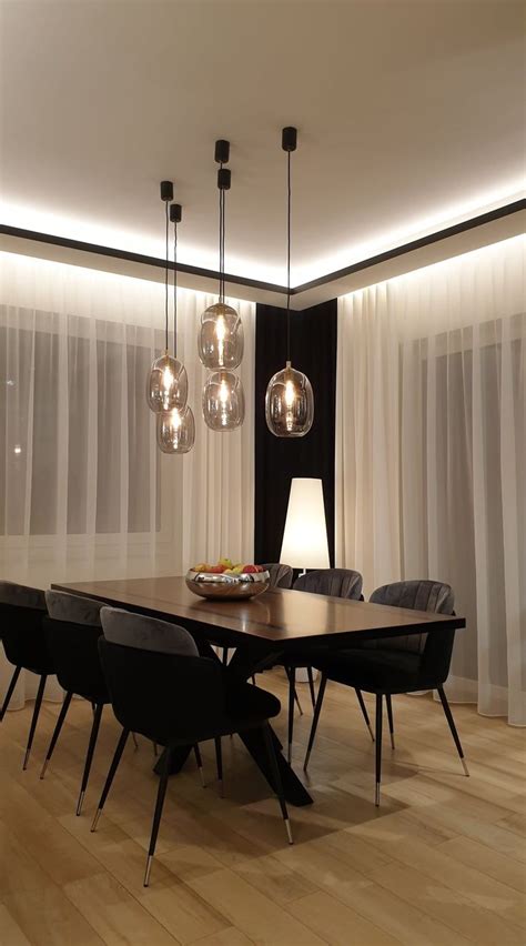 a dining room table and chairs with lights hanging from the ceiling