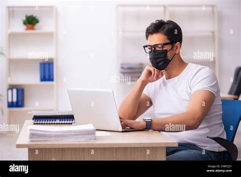 Young Student Employee Working At Workplace During Pandemic Stock Photo