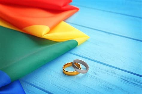Dos Anillos De Boda Y La Bandera Gay Del Arco Iris Sobre Fondo De Madera Foto Premium