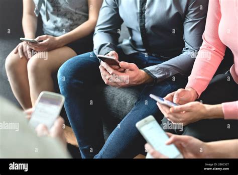 Group Of Millennial Business People Using Mobile Phones And Sitting On