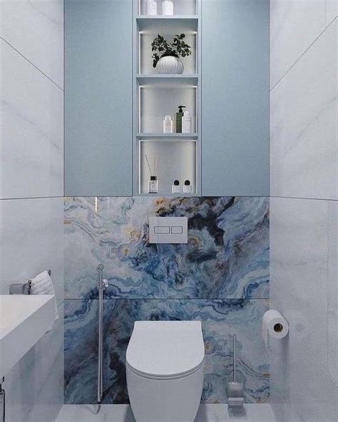 A White Toilet Sitting In A Bathroom Next To A Wall Mounted Shelf