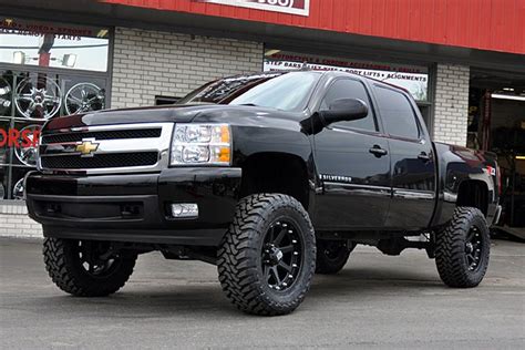 a large black truck parked in front of a building with tires on it's rims