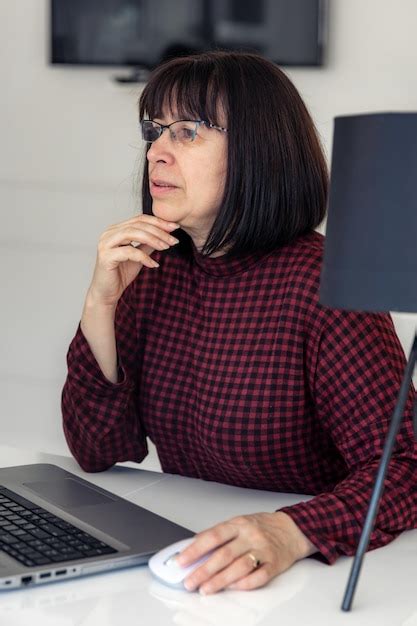 Mulher atraente de meia idade trabalhando em um laptop enquanto está