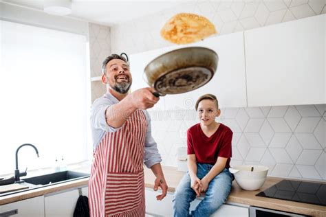 Mature Father With Small Son Indoors In Kitchen Flipping Pancakes Stock Image Image Of