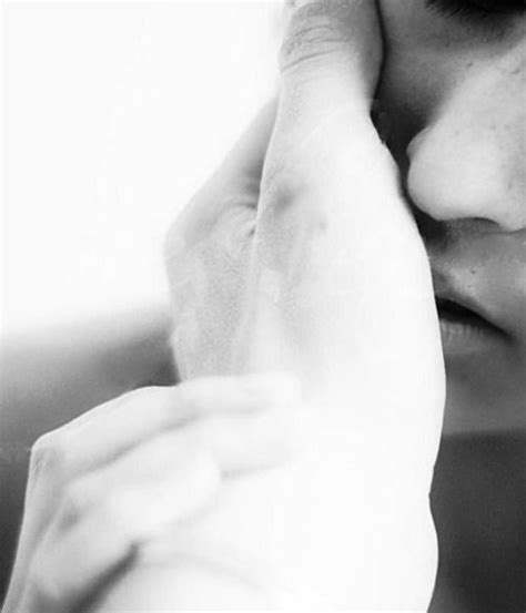 A Black And White Photo Of A Woman Holding Her Hand To Her Face