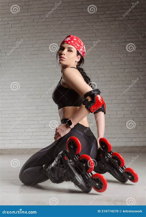 A Slender Woman In Sportswear On Roller Skates Is Sitting On The Floor