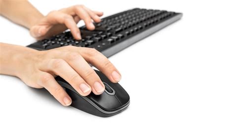 Las manos de la mujer usando el ratón y el teclado de la computadora