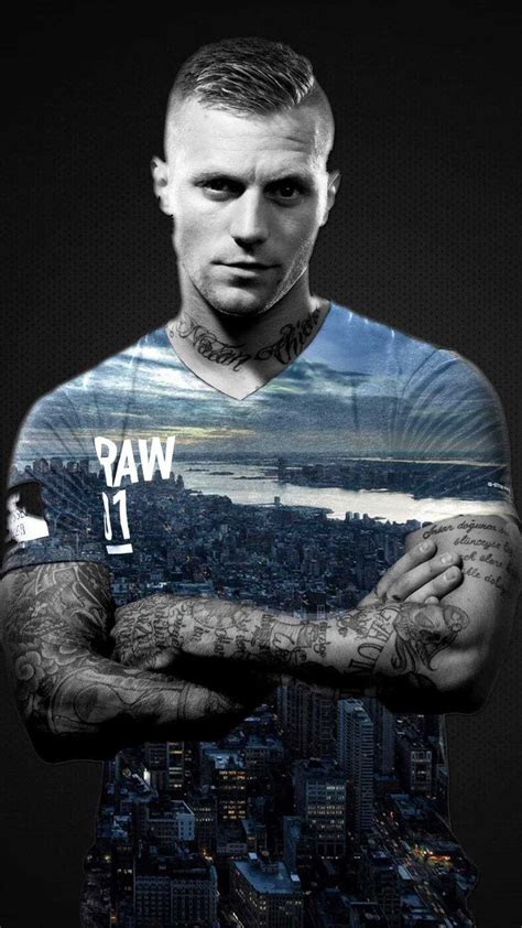 A Man With Tattoos On His Arm Standing In Front Of A Cityscape