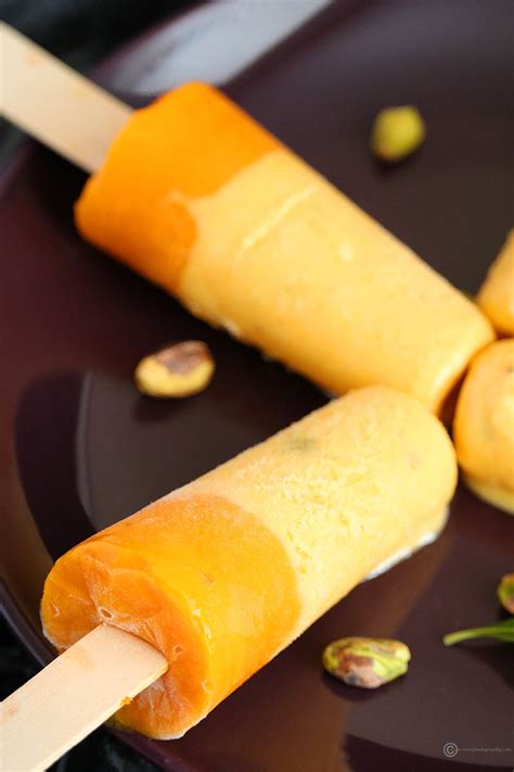 An Orange Popsicle Is Sitting On A Plate With Pistachios Around It