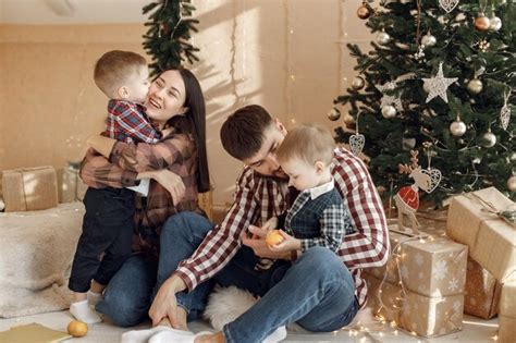 Fam Lia Jovem Em Camisas Xadrez Sentada Perto Da Rvore De Natal Foto