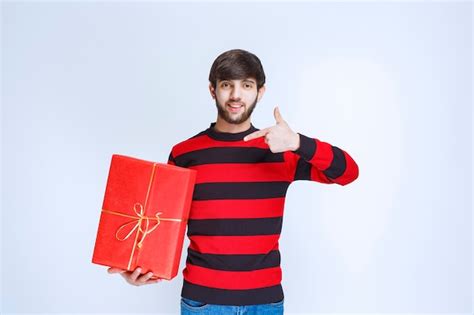 Hombre De Camisa A Rayas Rojas Sosteniendo Una Caja De Regalo Roja Y