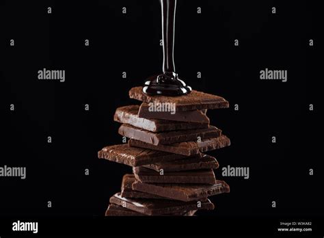 Hot Melted Dark Chocolate Pouring On Chocolate Stack Isolated On Black Stock Photo Alamy