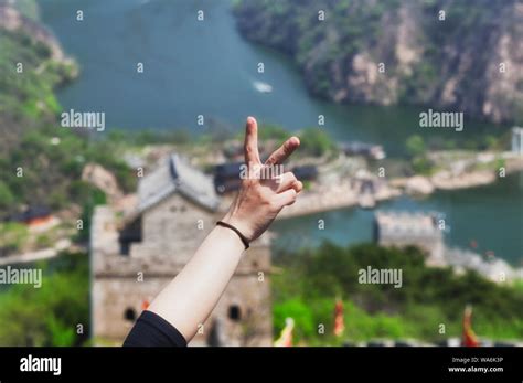 A Woman Flashing The Peace Sign With A Blurred Image Of The Great Wall