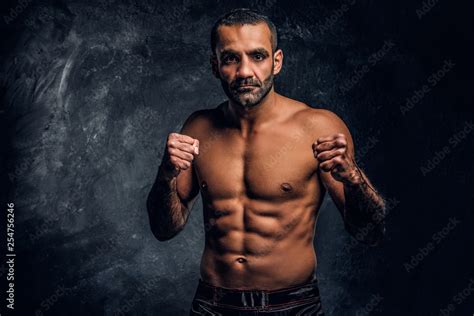 Professional Muay Thai Boxer With Naked Torso Posing For A Camera Studio Photo Against A Dark