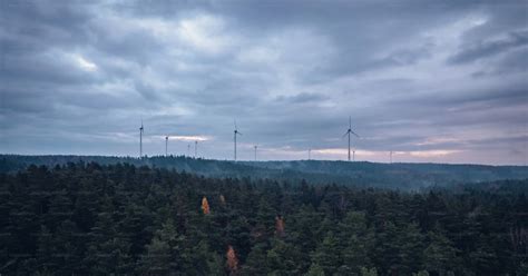 A Group Of Wind Mills Towering Over A Forest Photo Wind Turbine Image On Unsplash