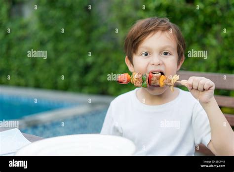 Cute Little Boy Eating Grilled Barbecue In House Stock Photo Alamy