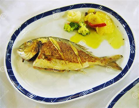 Baked Sea Bream Served With Potato And Vegetable Garnish Stock Image