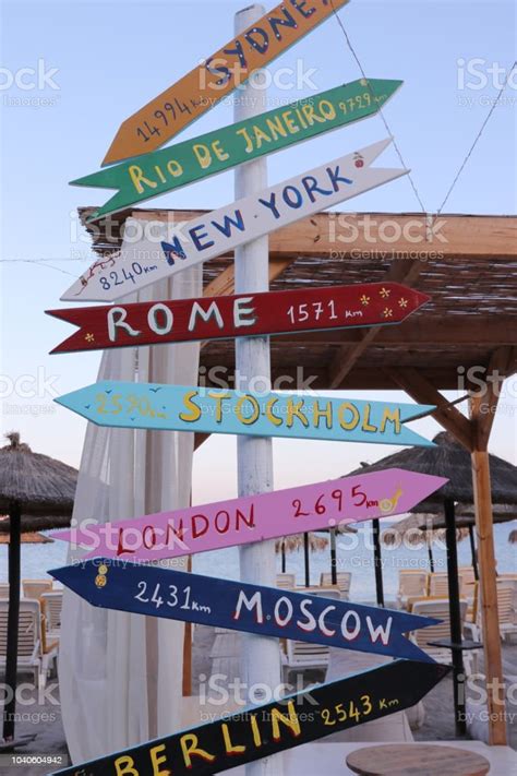 Direction Signpost On The Beach With Distances To Many Different